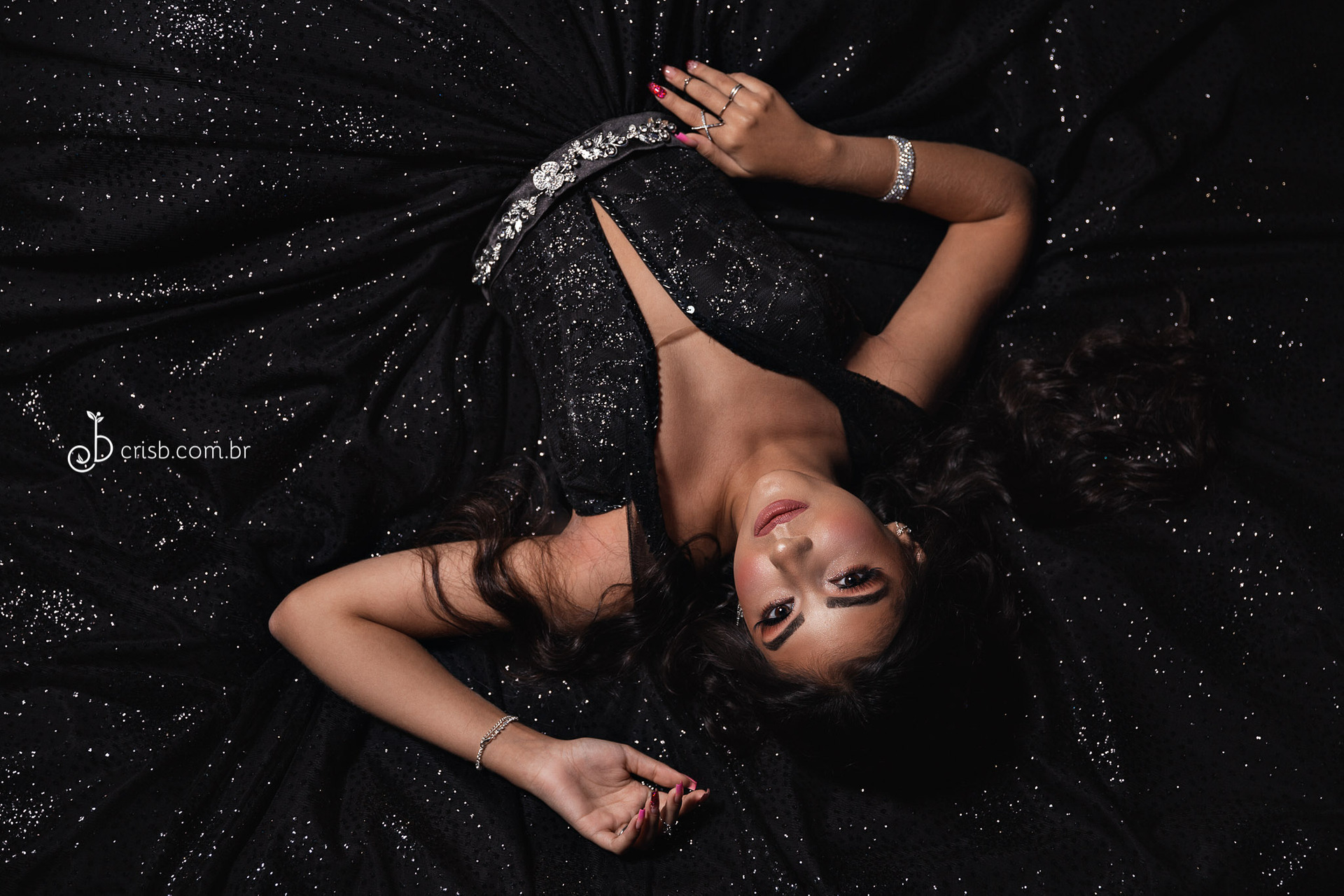 Fotografia de debutante com luz bem marcada em que olha para mesa de lembrancinhas numa pose elegante e com vestido azul fotos de 15 anos na SVM Festas em Piedade no Rio de Janeiro