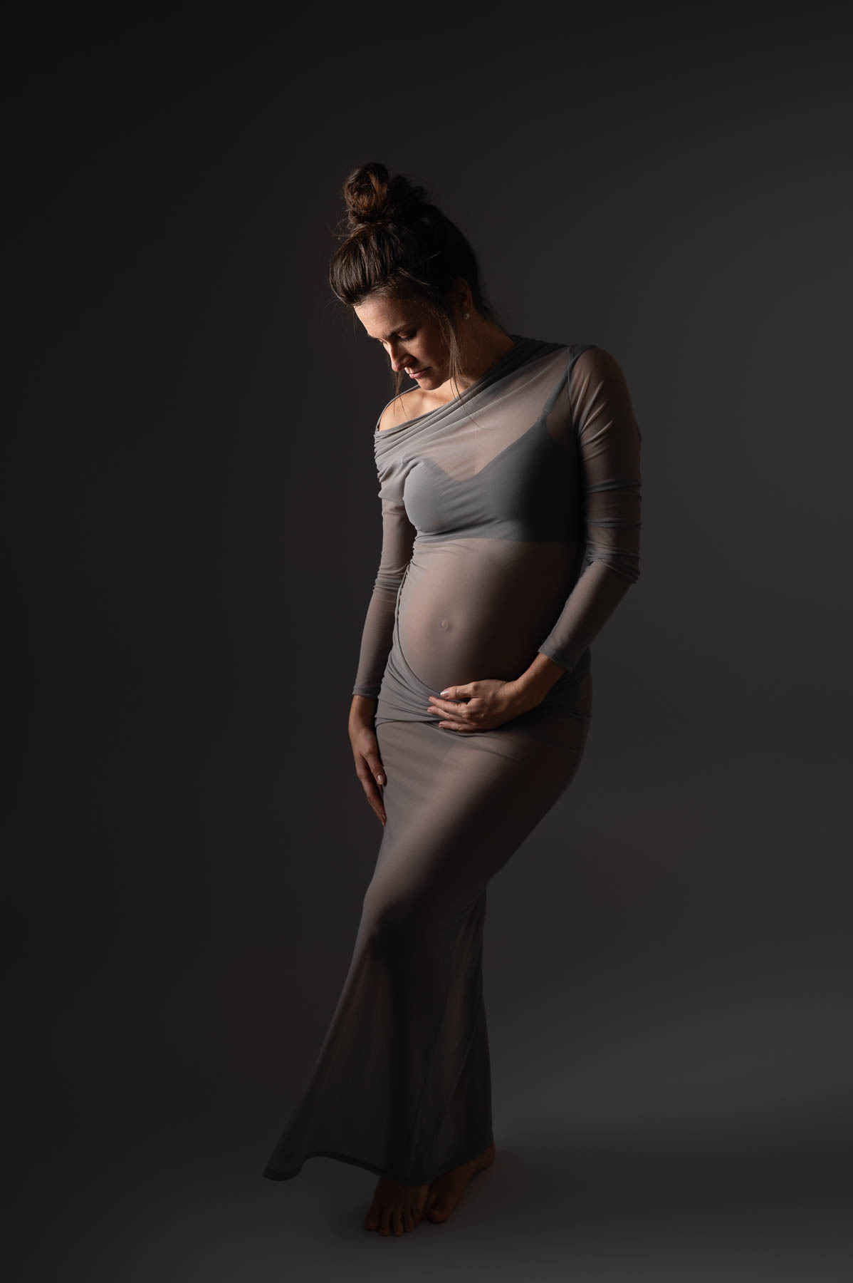 gestante olhando para a barriga de forma elegante com luz artistica em estudio especializado na Vila Leopoldina em São Paulo/SP