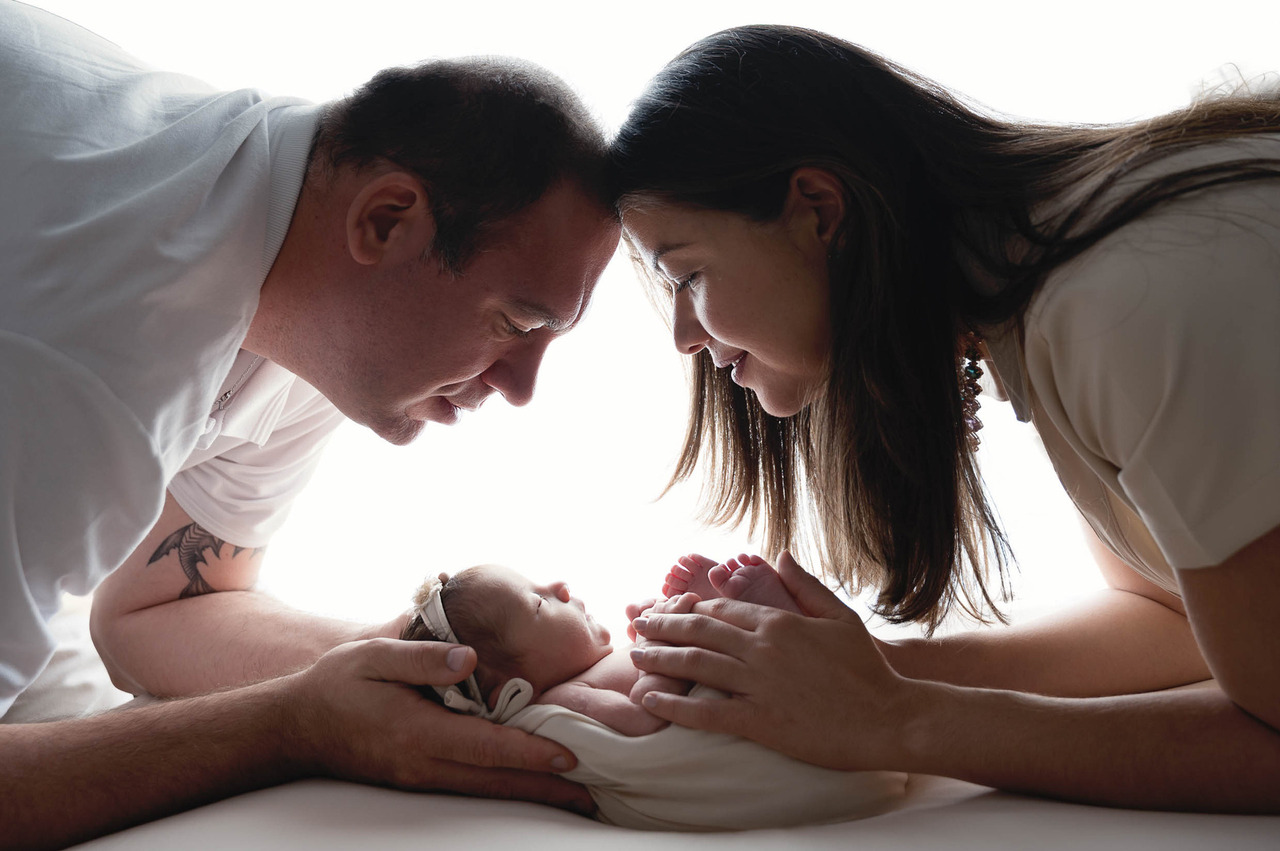 Pais segurando seu bebê recém-nascido durante ensaio newborn em estúdio na Vila Leopoldina em São Paulo