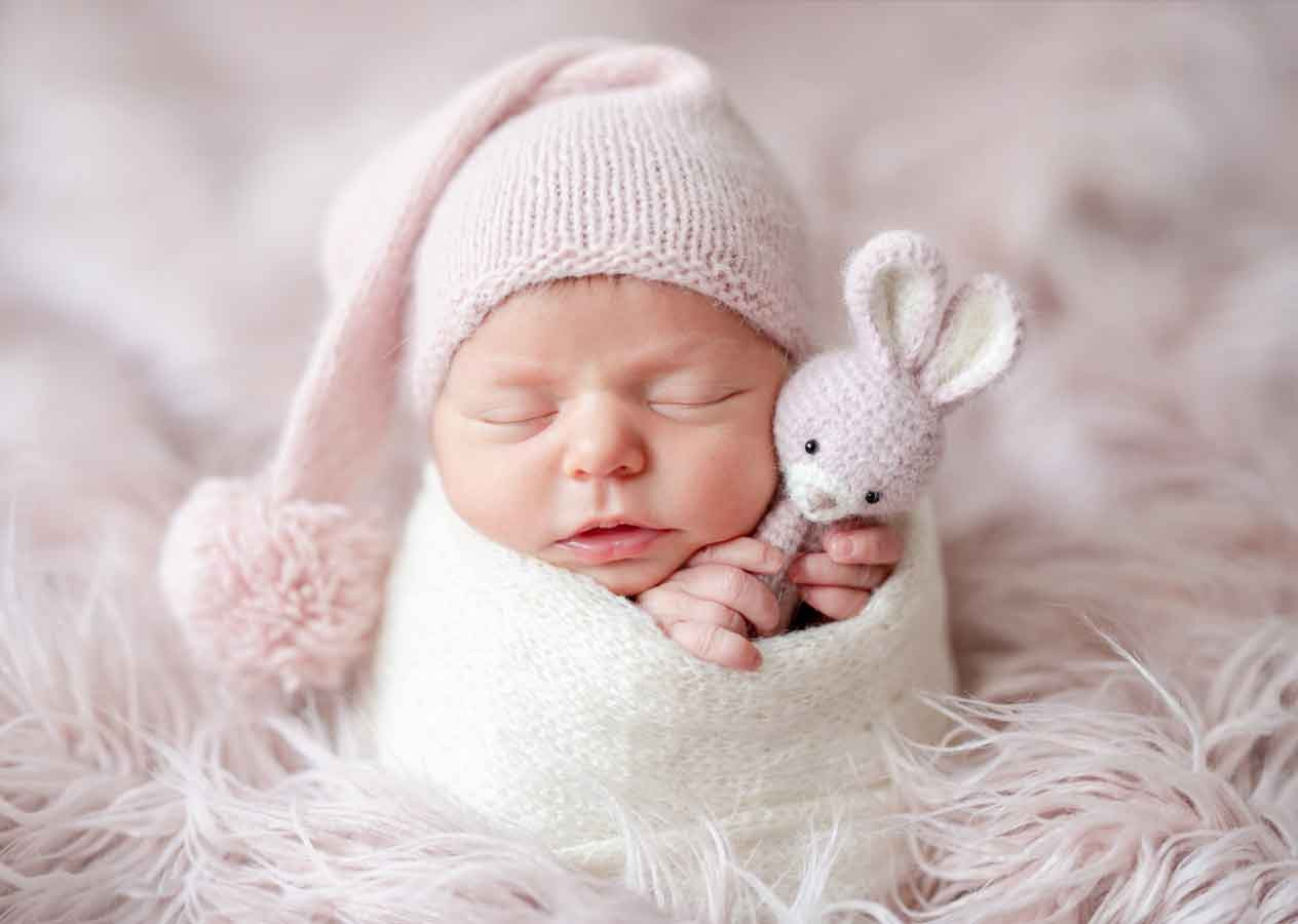 Recém-nascido dormindo em pose fetal com manta macia