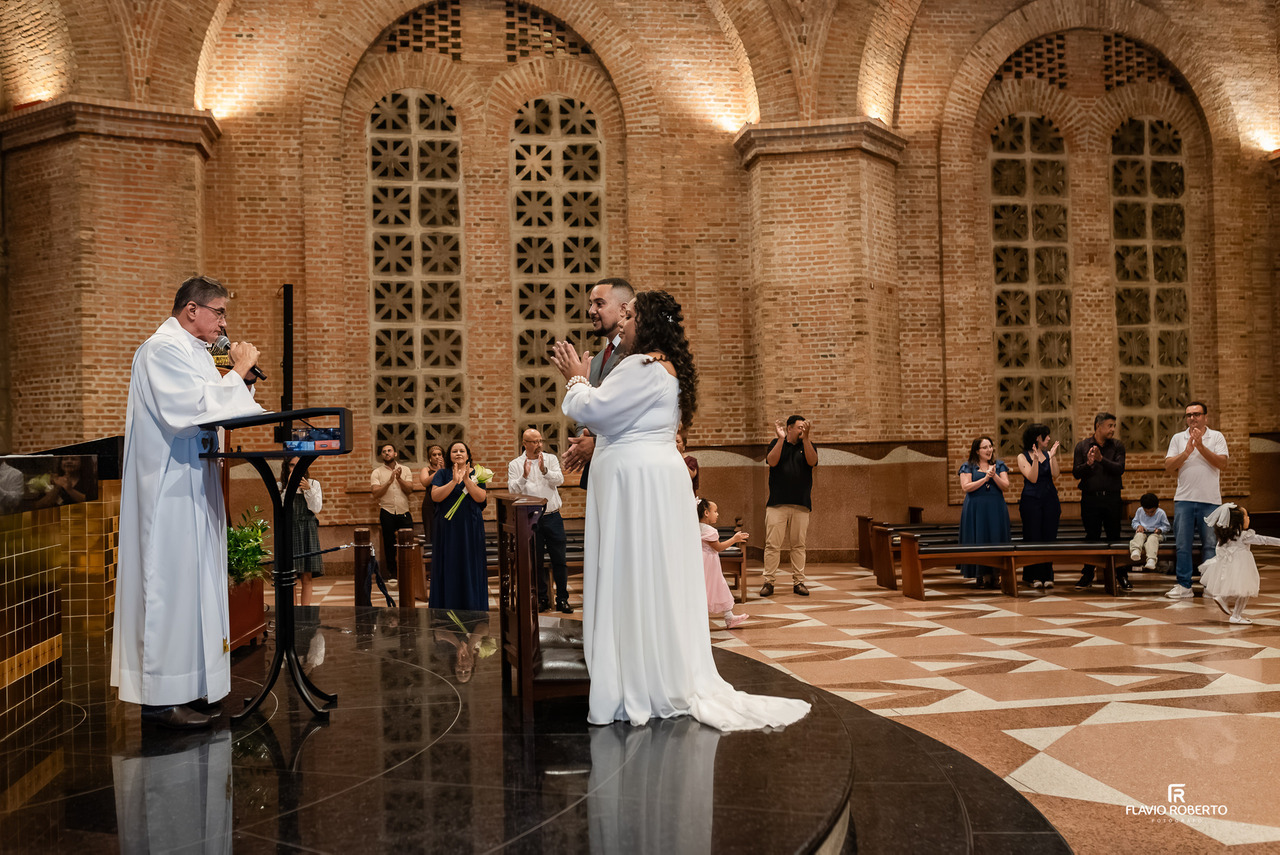 Padre celebrando casamento religioso no Santuário Nacional de Aparecida com noivos diante do altar