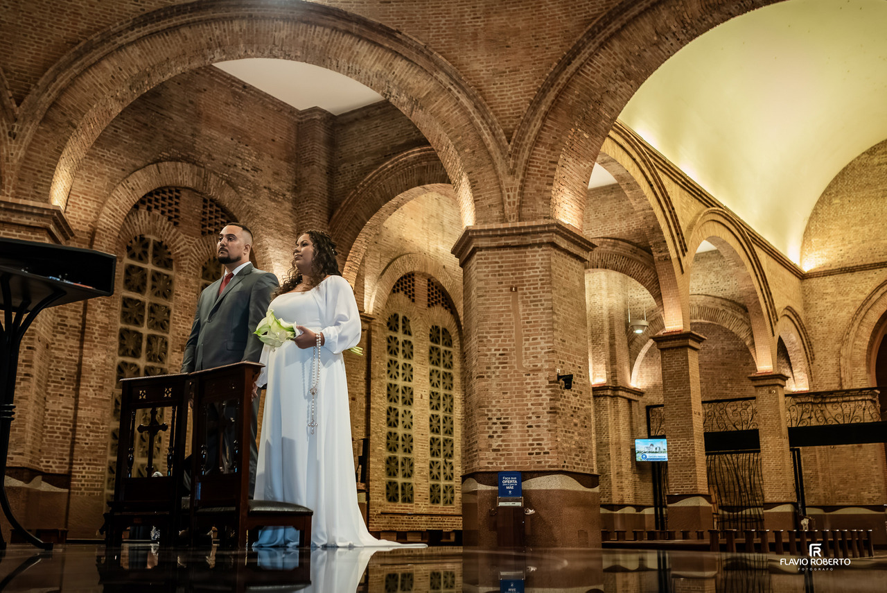Noivos em momento solene no altar do Santuário Nacional de Aparecida com arquitetura em destaque