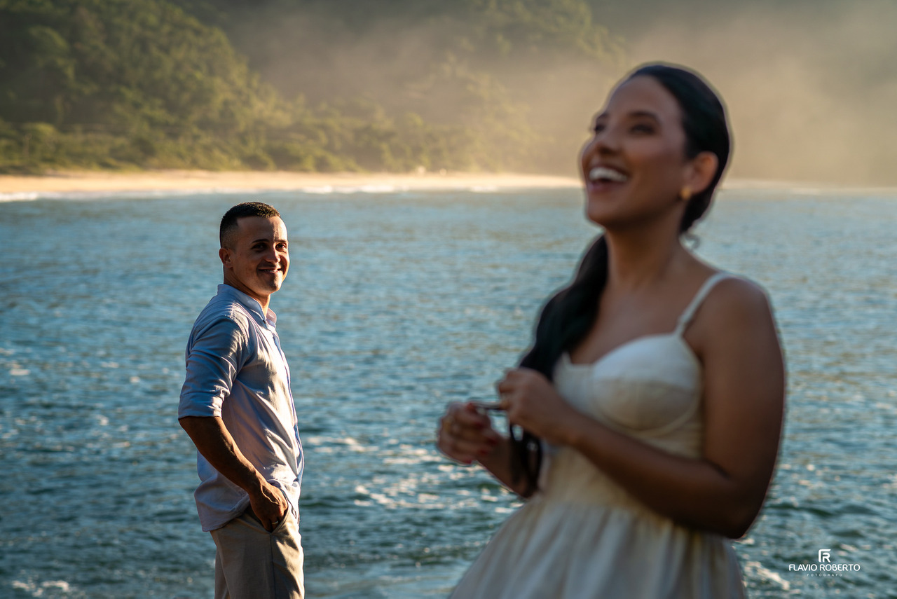 Noivo olhando para a noiva durante ensaio na praia em Ubatuba, com foco na emoção e conexão do casal.