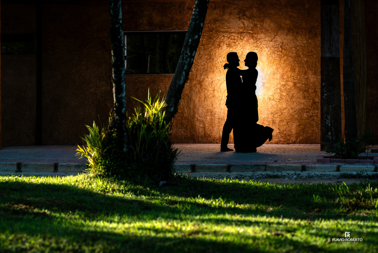 Silhueta de casal em ensaio pré-wedding com iluminação dramática e composição artística, destacando formas e emoção.