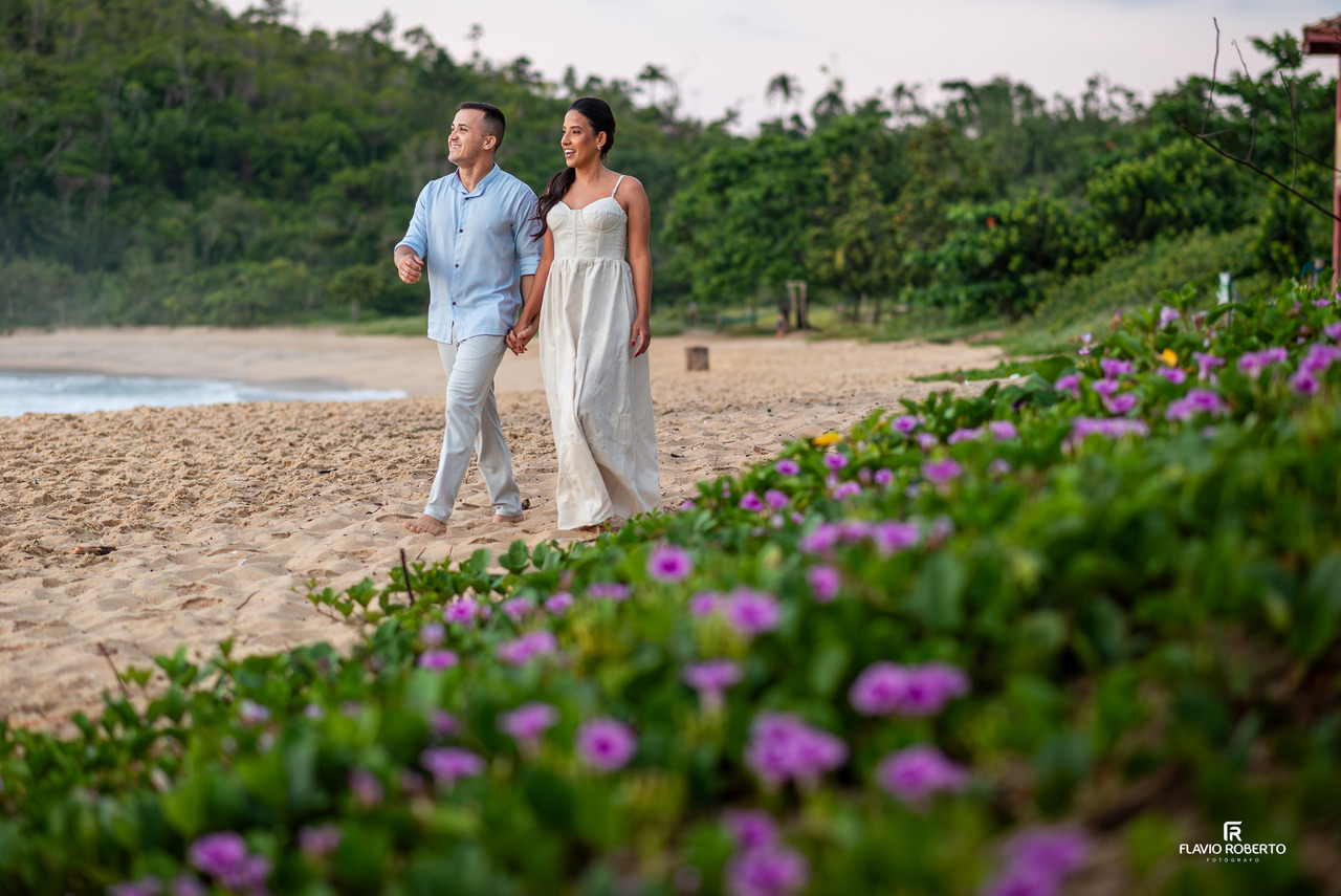 ensaio pré wedding em Ubatuba casal andando na praia com flores em primeiro plano