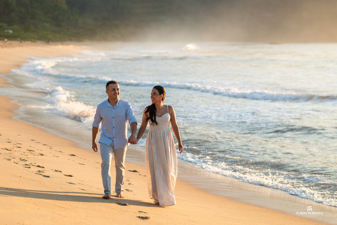 pré wedding em Ubatuba casal caminhando na praia com luz dourada e mar ao lado