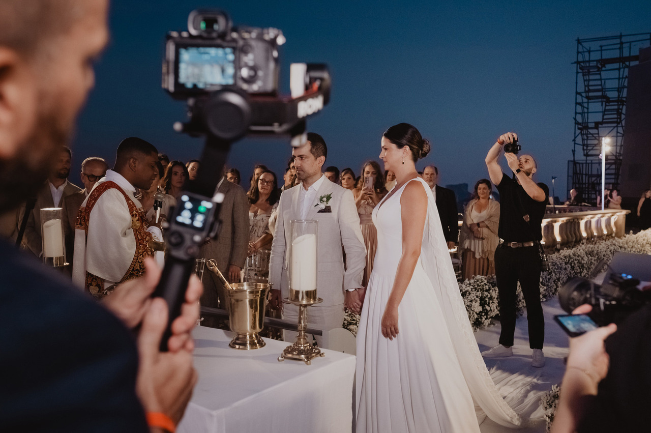 Cerimónia de casamento ao anoitecer com o videógrafo e os fotógrafos a registar os noivos no altar