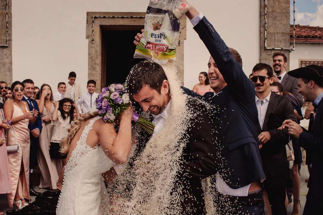 Padrinho despeja um saco de arroz sobre os noivos à saída da igreja, no dia do casamento