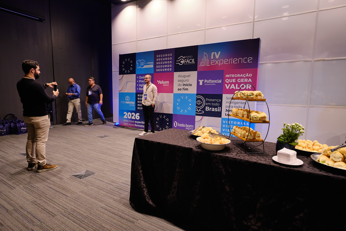 participantes do evento usando o backdrop para fazer fotos com celular