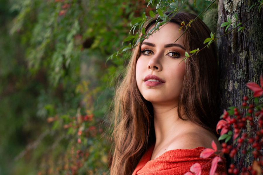 fotos em dois irmaos-sessao fotografica em dois irmaos-dois irmaos rs-ensaio de fotos dois irmaos rs-gatota bonita com blusa laranja encostada em uma arvore com frutinhas vermelhas e plantas ao redor-fotografia feminina porto alegre