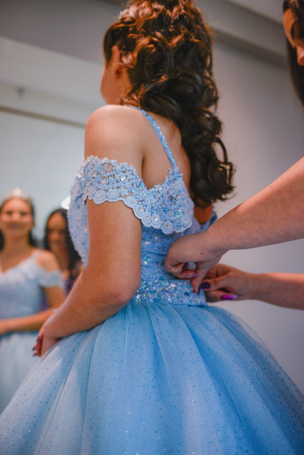 mãe ajusta o vestida da filha na sua noite de debutante