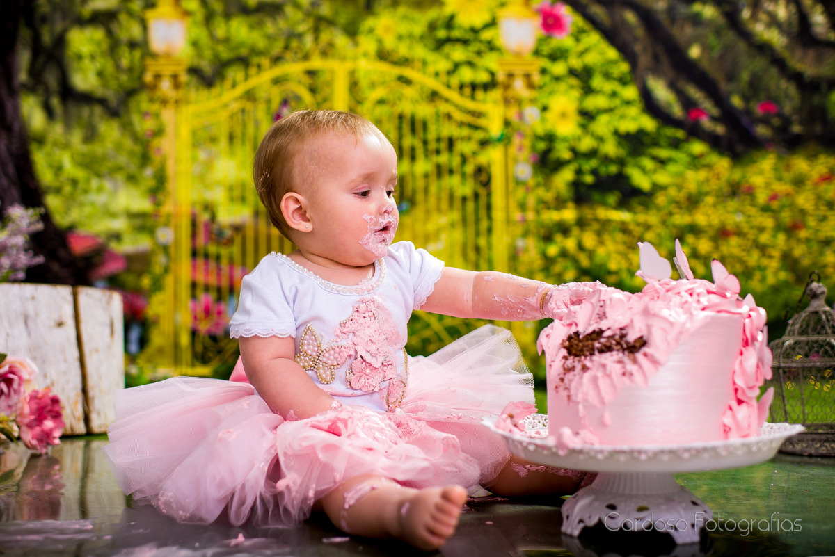menina em ensaio fotográfico smash the cake com saia de tutu e bolo rosa