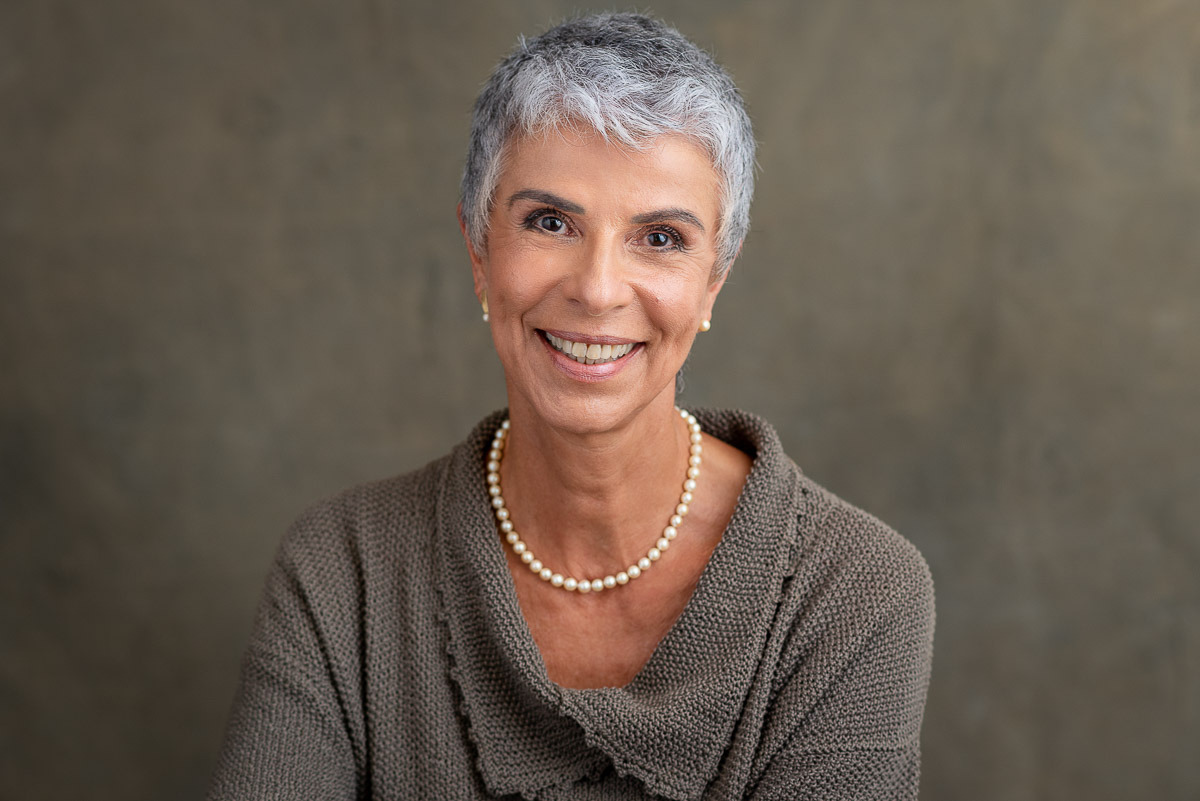 Headshot de mulher sorrindo em fundo neutro, ideal para LinkedIn e site profissional