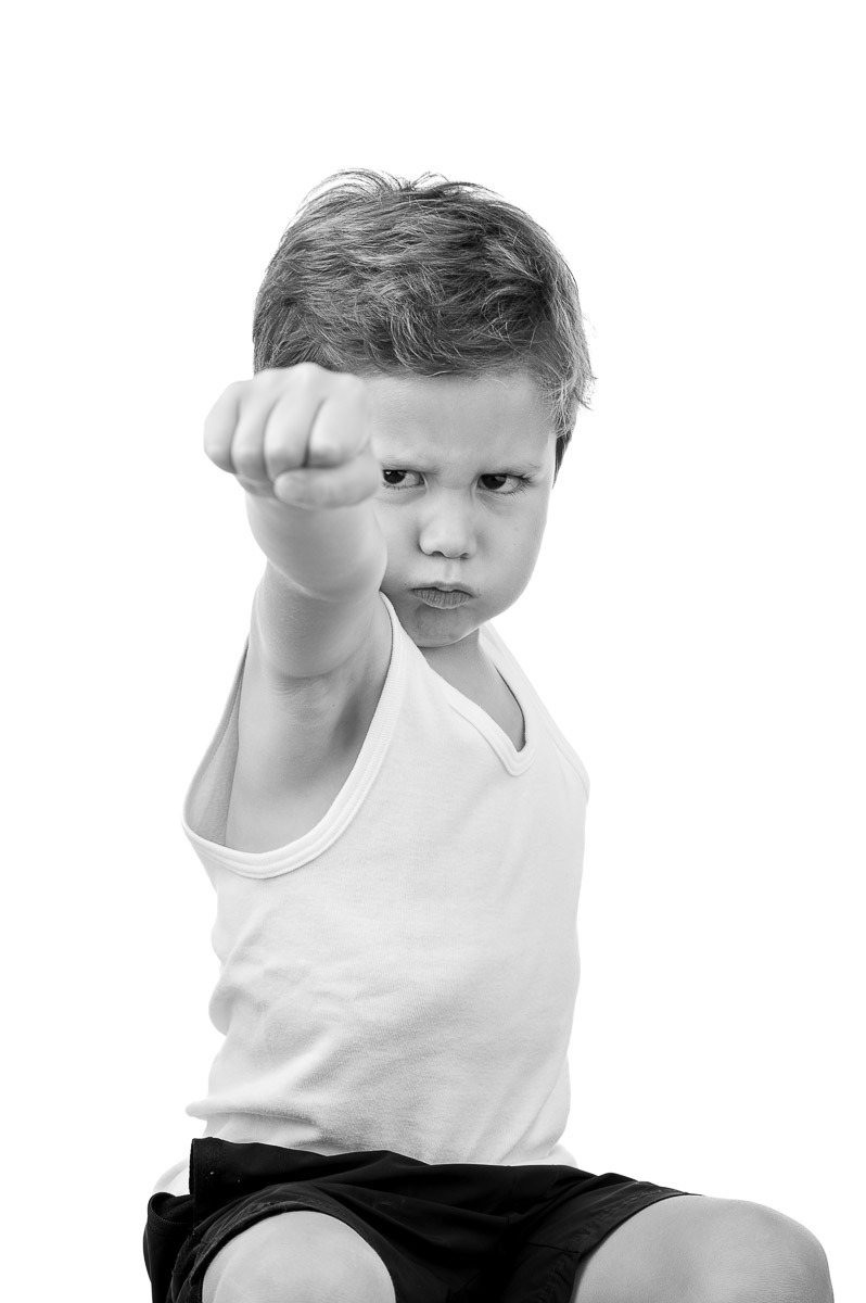 Retrato divertido de menino fazendo pose de super-herói em estúdio com fundo branco