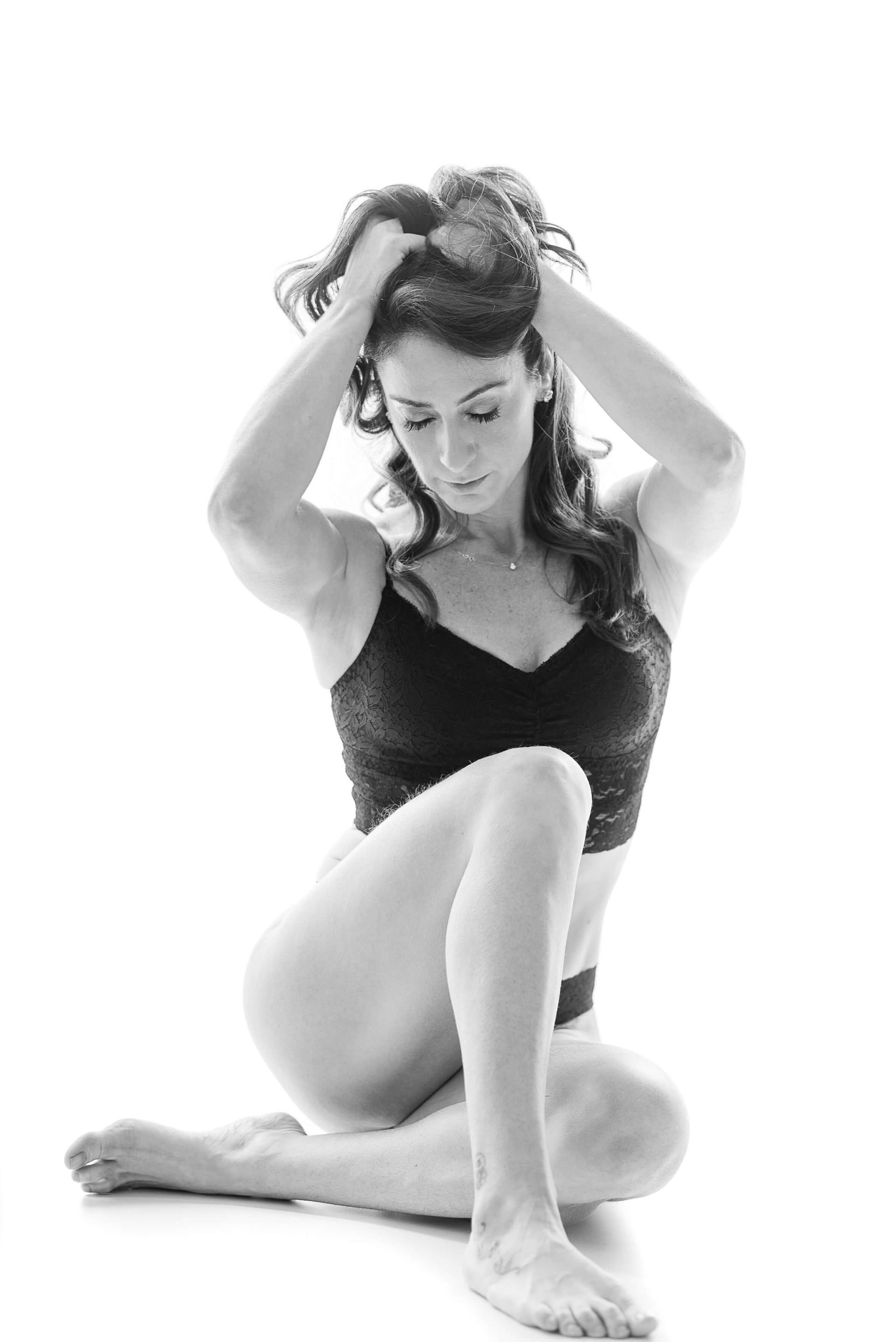 Retrato feminino em look festivo com vestido de franjas azul, sorriso aberto e pose confiante. Ensaio em estúdio com fundo branco e luz controlada.