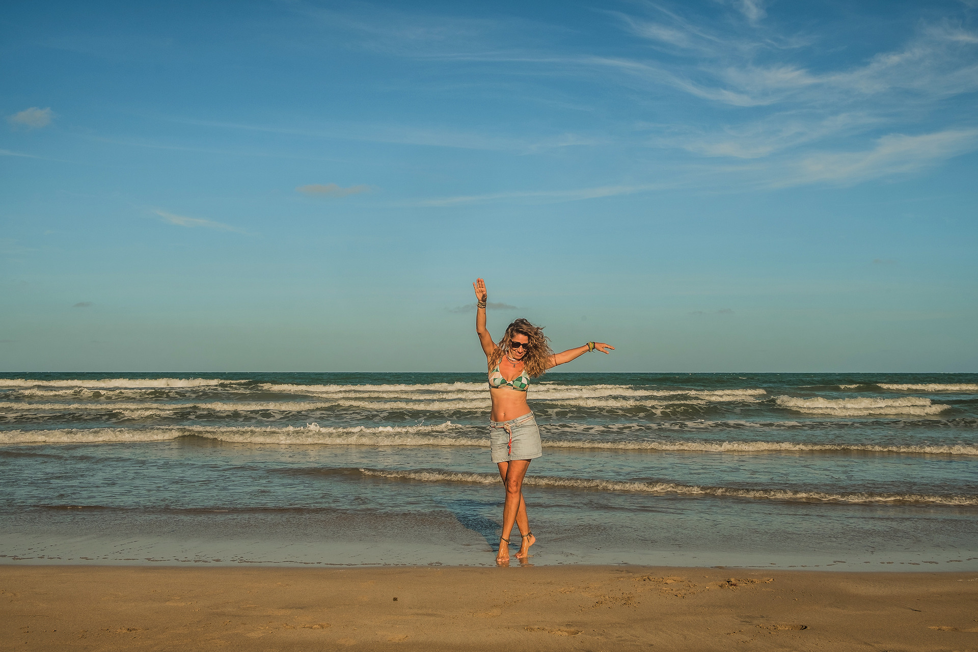 Fotografia espontânea de mulher sorrindo durante ensaio feminino na praia.