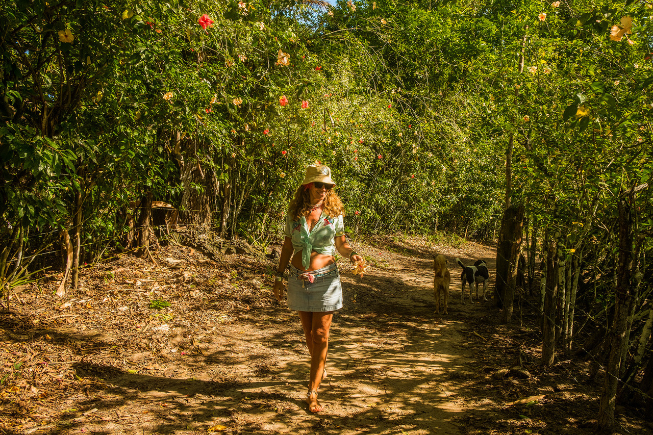 Mulher entre flores da Trilha dos Hibiscus durante ensaio feminino em Boipeba, Bahia, registrando uma experiência de conexão com a natureza.