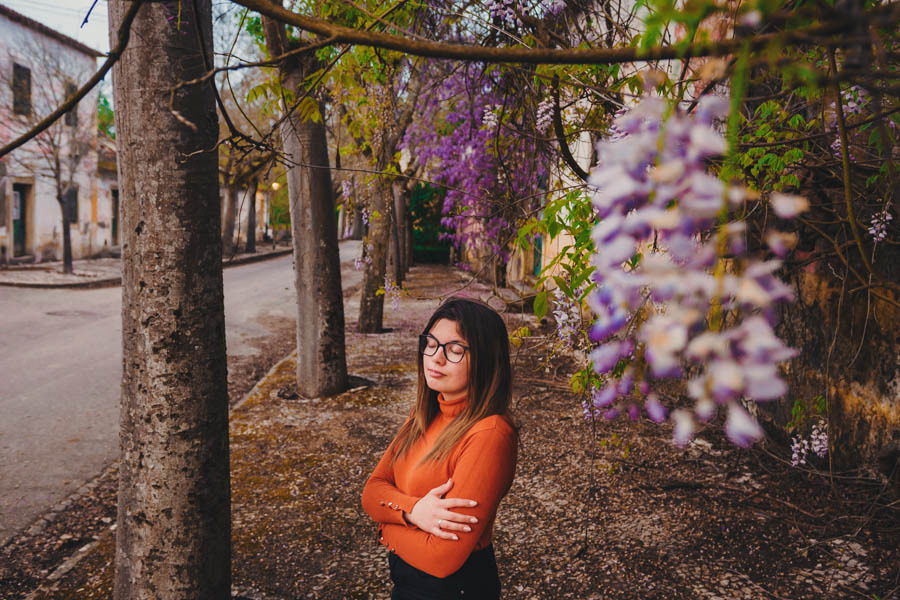 Mulher de laranja rodeada de glicínias durante sessão fotográfica de retrato na Quinta da Cardiga, Goleã