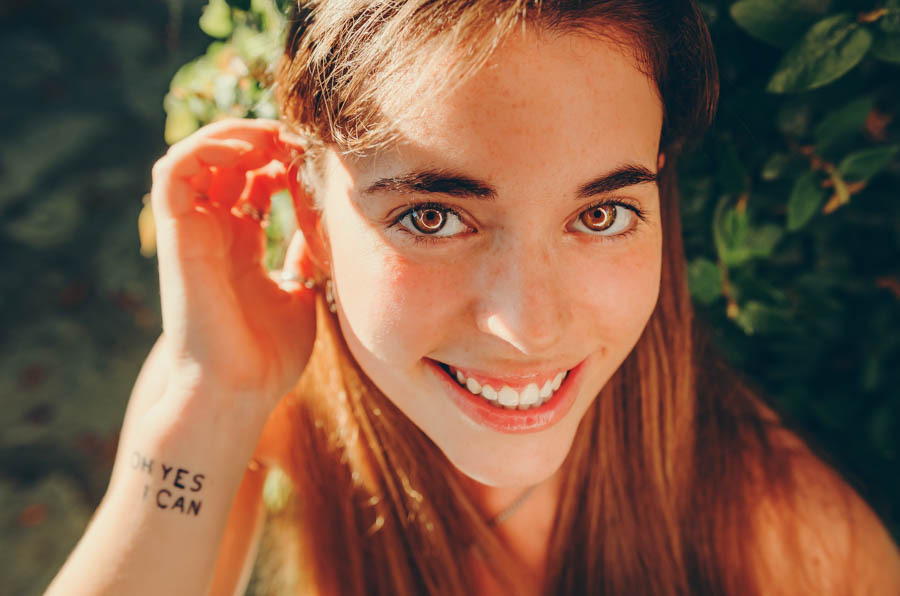 Jovem mulher a sorrir com flores silvestres ao ar livre em sessão fotográfica de retrato natural e espontâneo — Duo Capuano