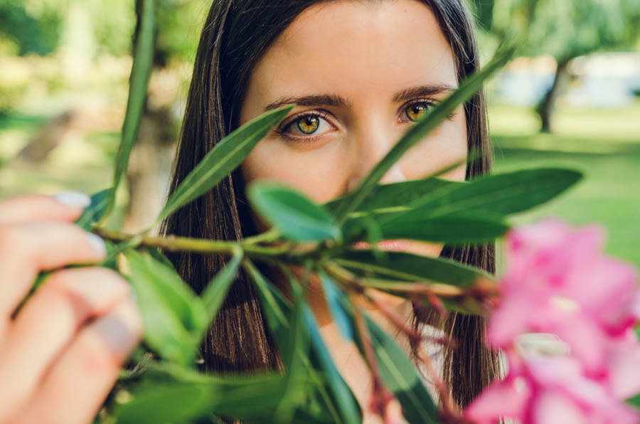 Mulher entre folhagem com olhar intenso durante sessão fotográfica de retrato feminino no Parque do Bonito, Entroncamento