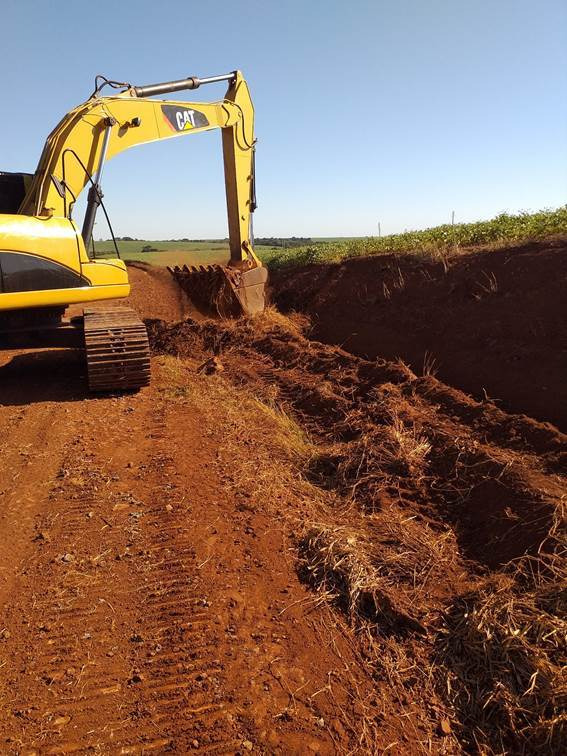Retroescavadeira realizando escavação da lateral da via