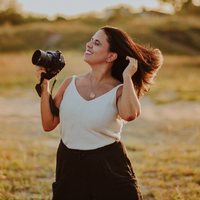 fotógrafa feliz segurando sua camera com cabelos voando ao vendo em um por do sol
