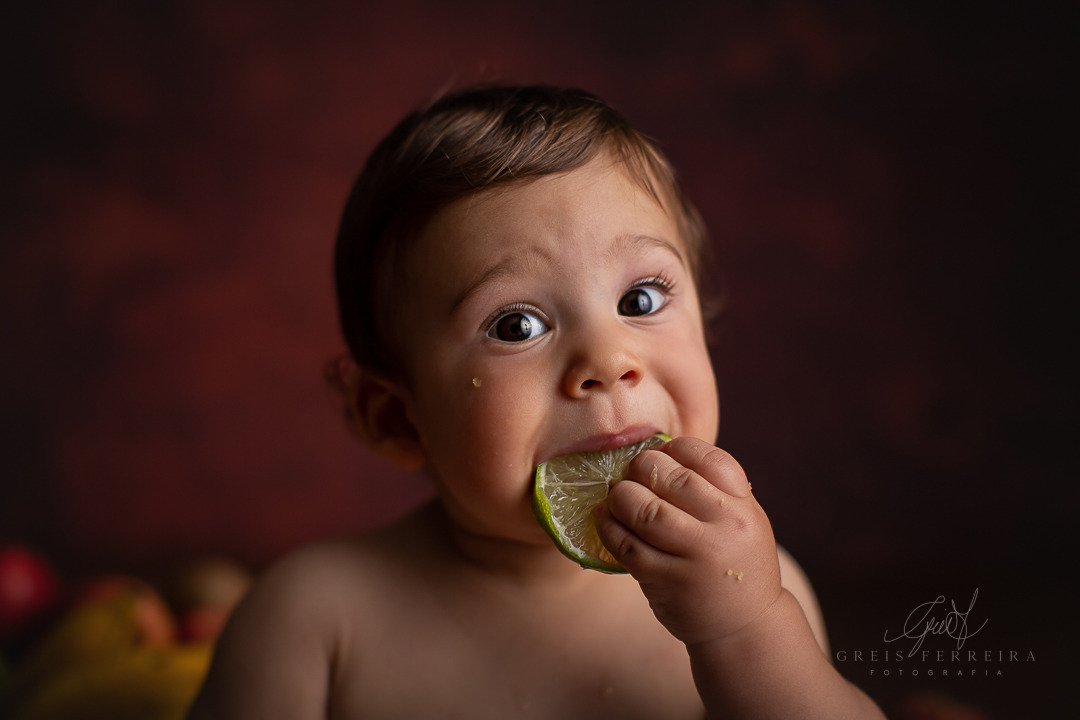 ensaio de bebe com frutas chupando limão