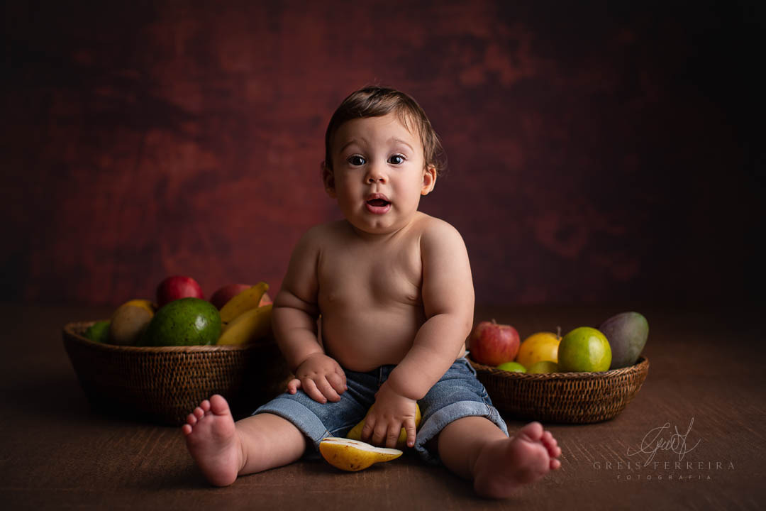 ensaio de bebe com fruta comendo pera