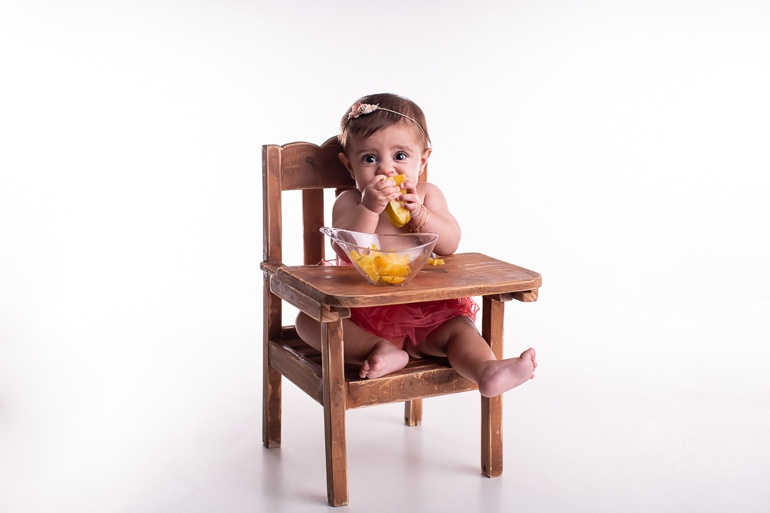 ensaio de bebe com fruta carambola no cadeirao fundo branco