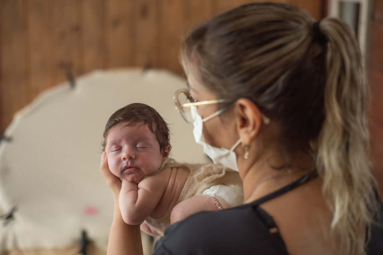 fotógrafa Aline Fontes segurando bebê em suas mãos para preparar o ensaio newborn