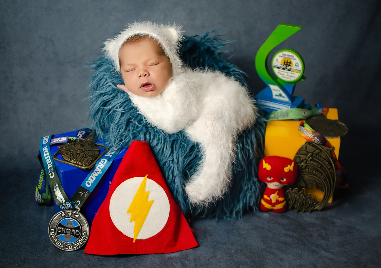 bebê rodeado de medalhas e troféus alusivos ao dia do atletismo e homenagem ao pai, corredor de rua fotografado pela fotógrafa Aline Fontes