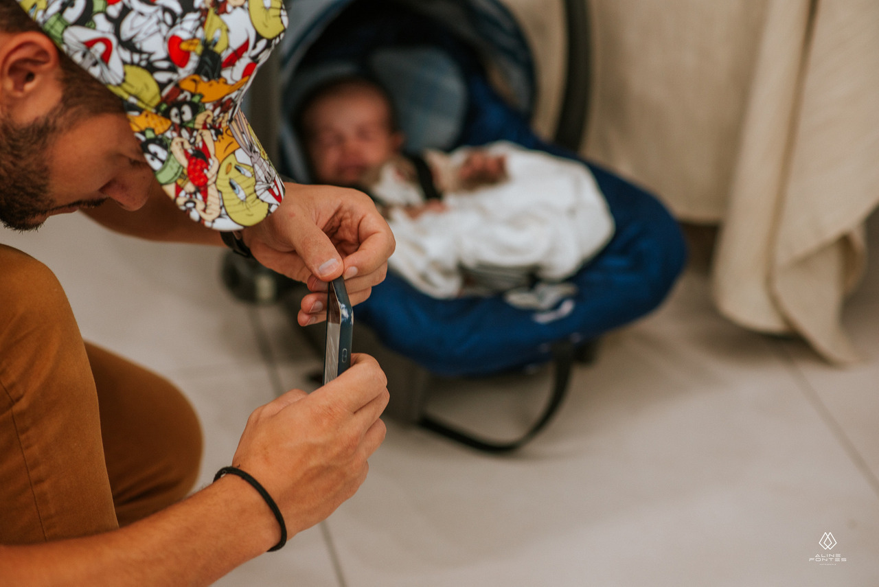 homem fotografando com o celular na academia junto a um bebê