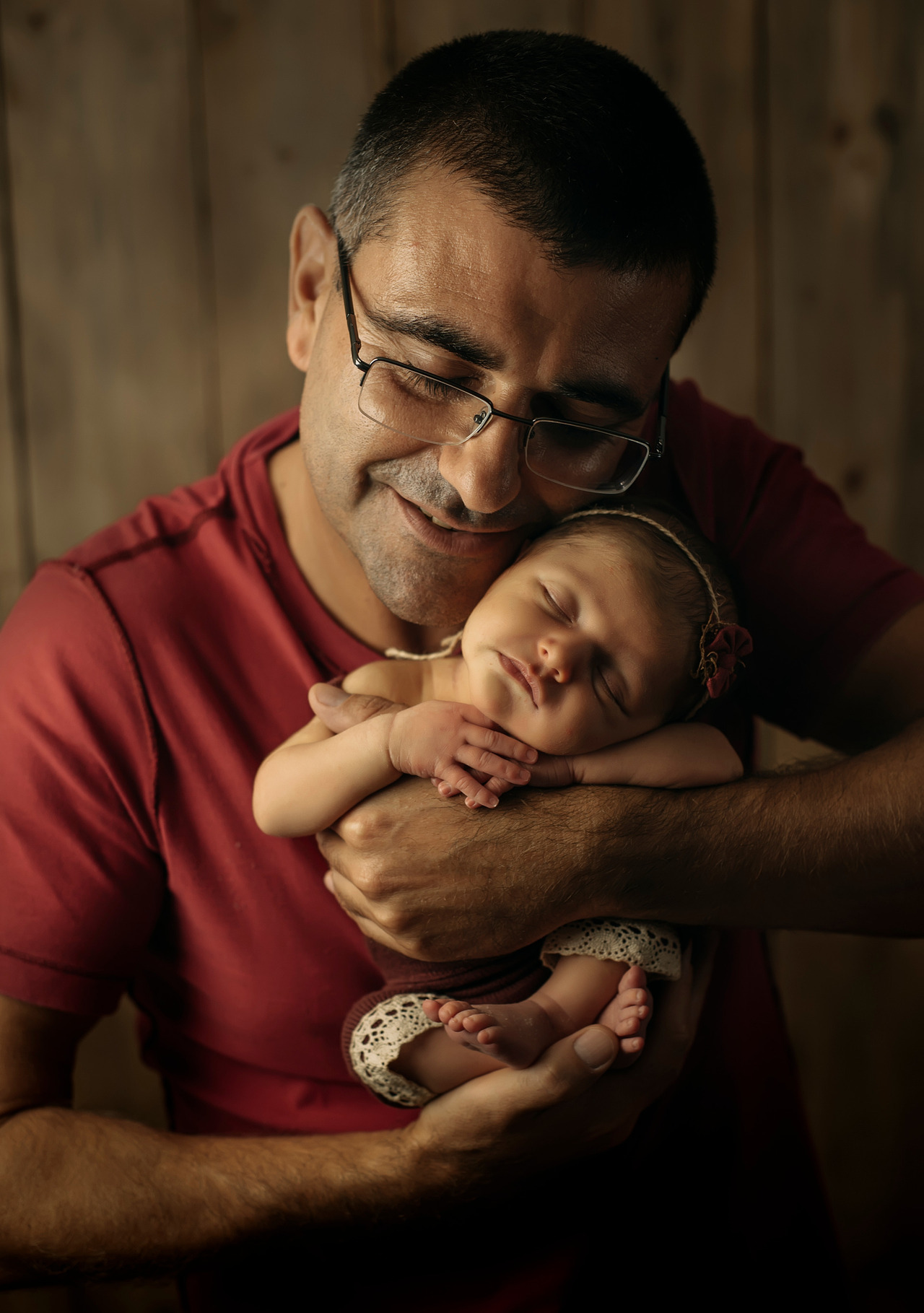 pai segurando bebê recém-nascido no colo em ensaio newborn