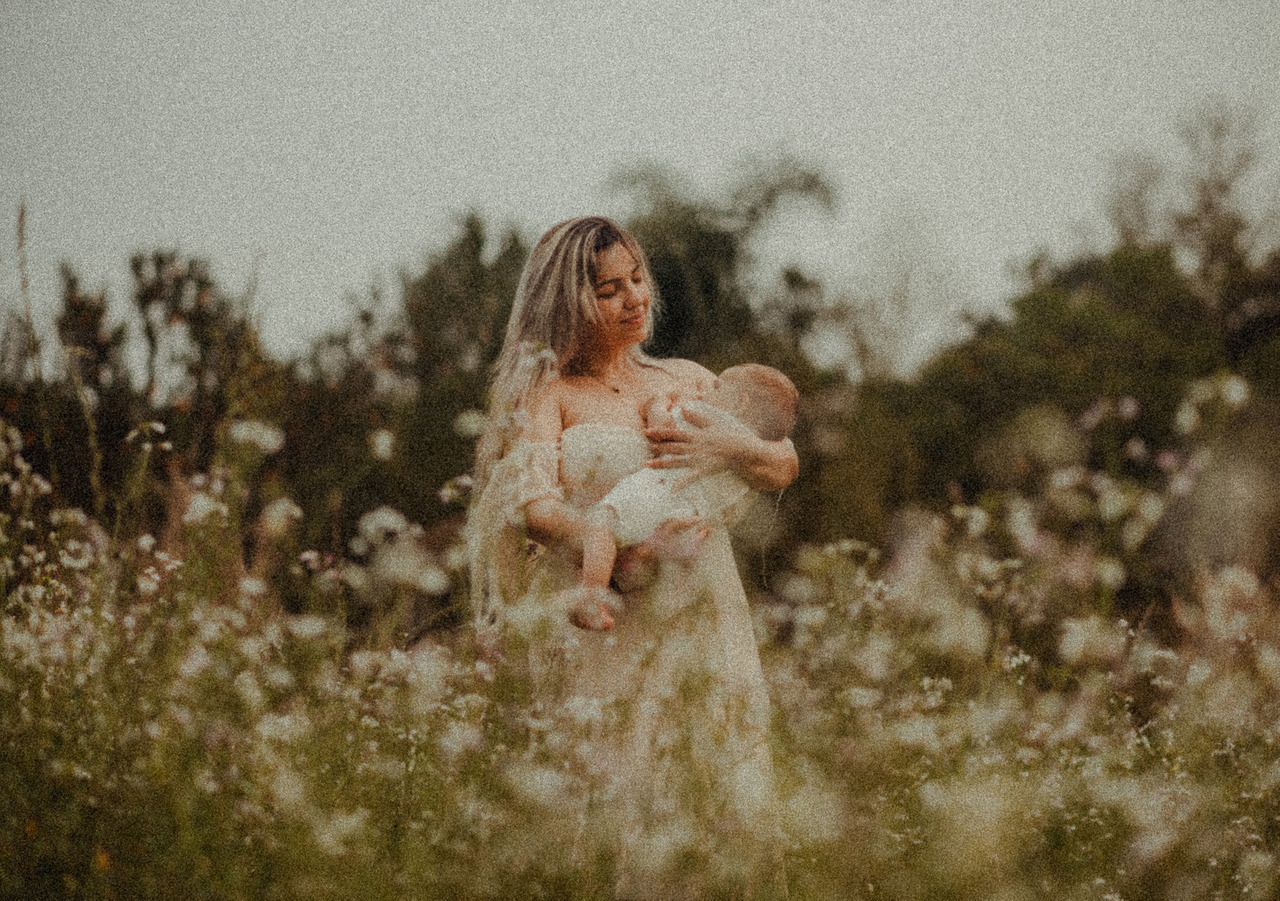 Aline Fontes amamentando bebê em campo florido