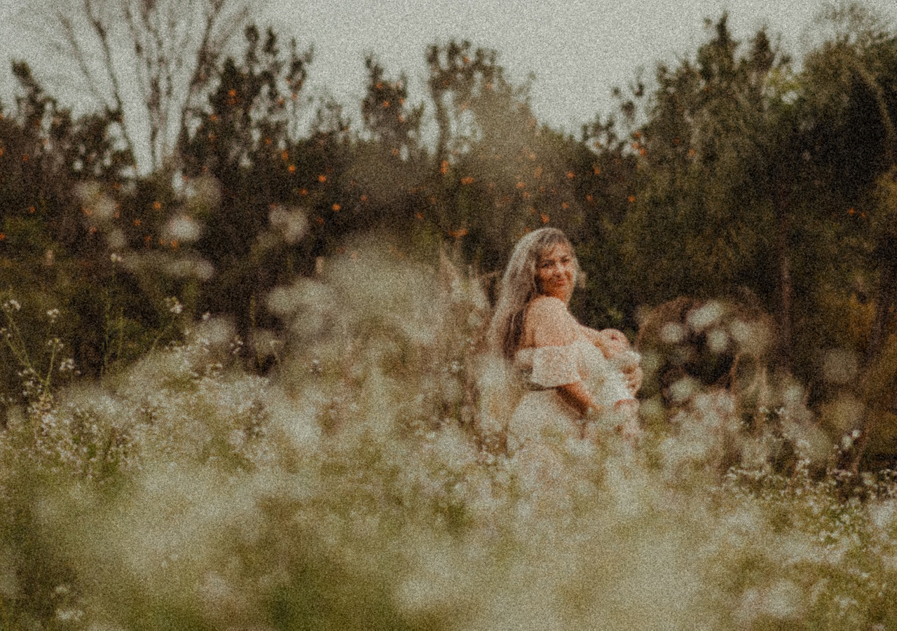 mulher amamentando bebê entre as flores