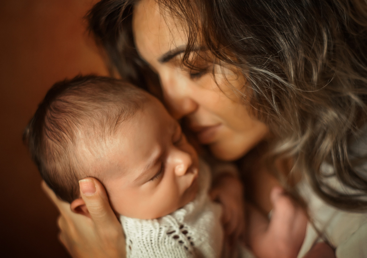 Mãe com bebê recém-nascido no colo, em guia da fotógrafa Aline Fontes para mães sobre fotos dos filhos nas redes sociais, imagem infantil e privacidade.