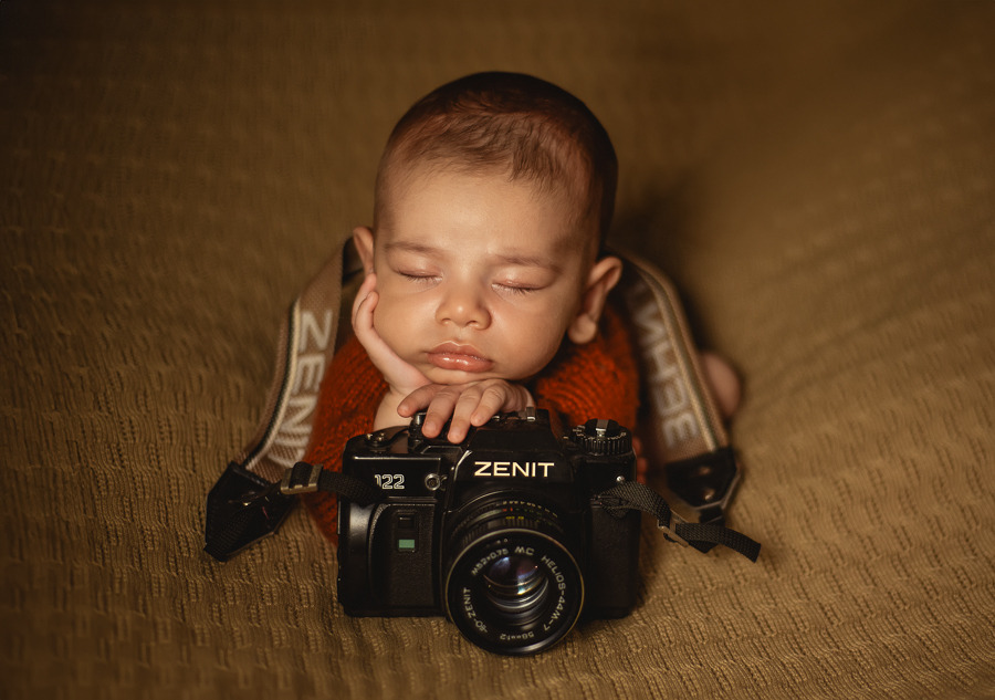 Filho da fotógrafa Aline Fontes segurando uma câmera fotográfica em registro familiar, representando memória de infância, fotografia e compartilhamento consciente de imagens dos filhos.