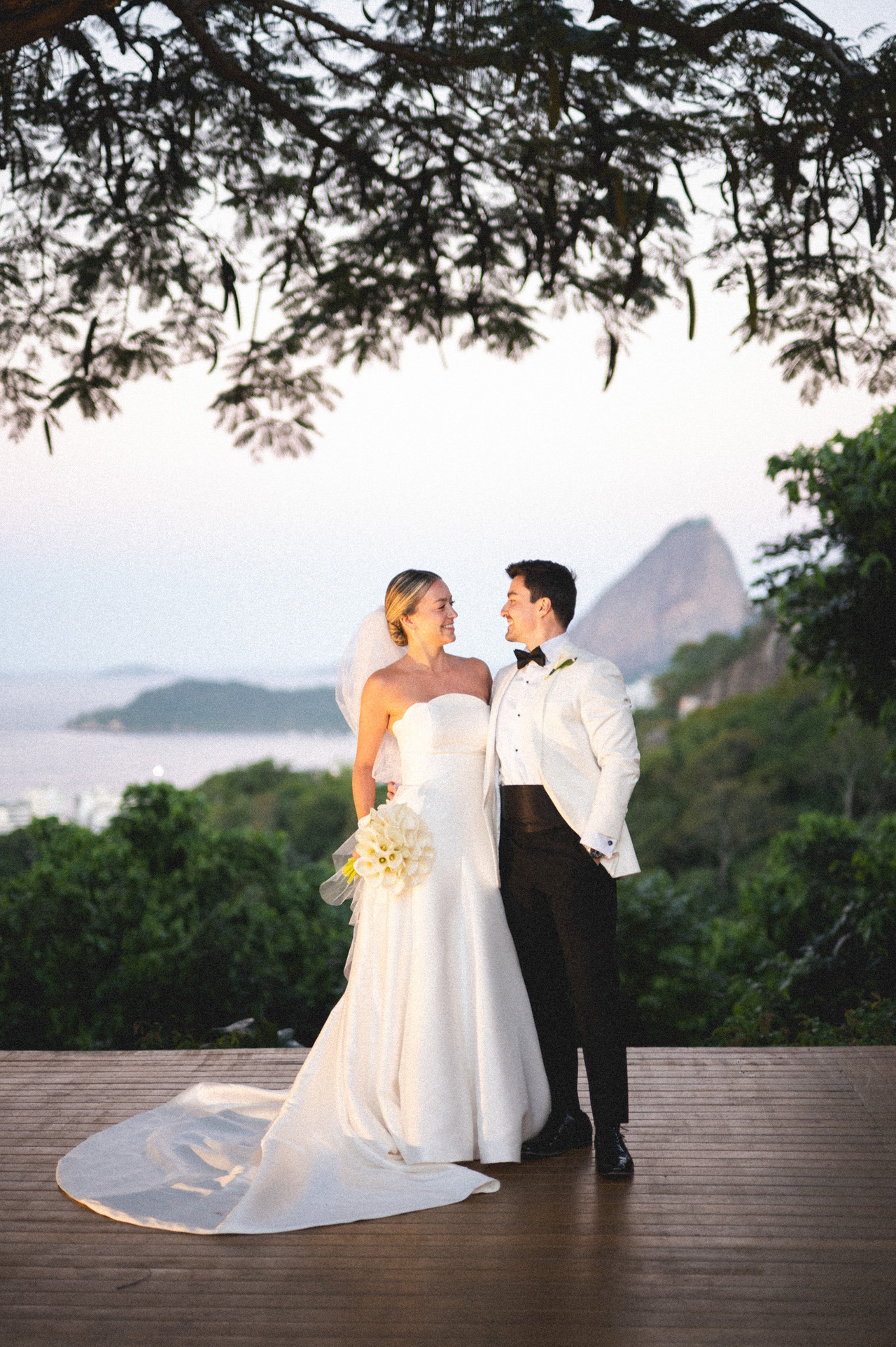destination wedding, casal de noivos se olha enquanto fotografo faz fotos com o pão de açucar ao fundo