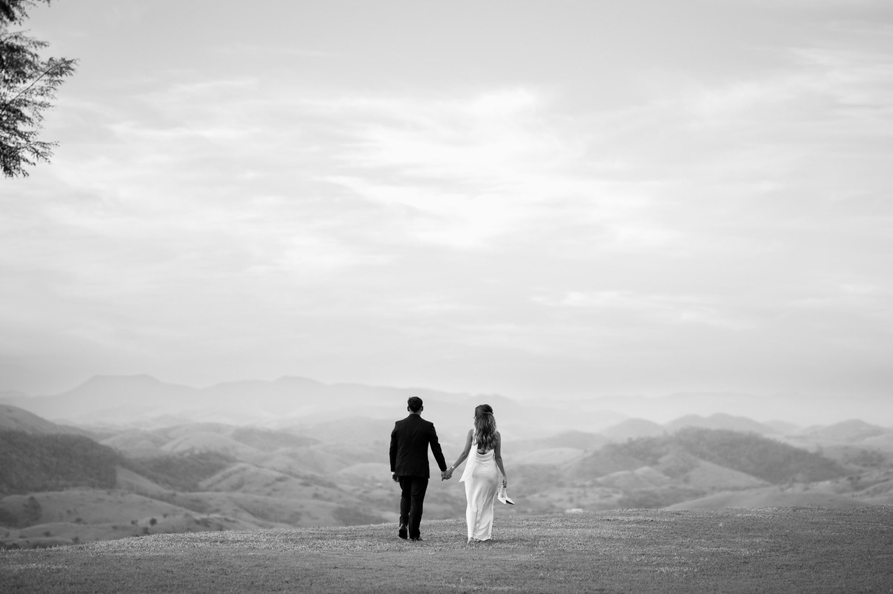 casal caminha no gramado em direção as montanhas apos cerimonia de casamento no vale dos desejos em areal