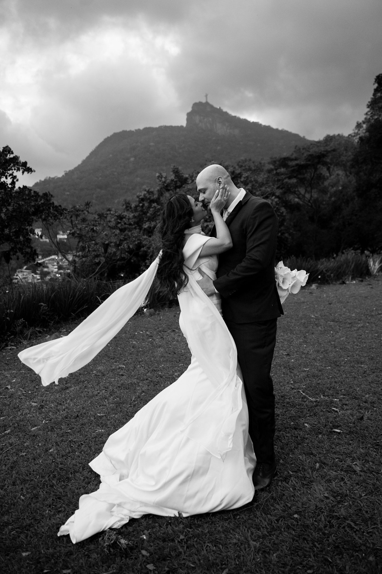 casamento com vista para o cristo redentor casal se beija em meio a ventos fortes trazendo uma fotografia romantica e autoral