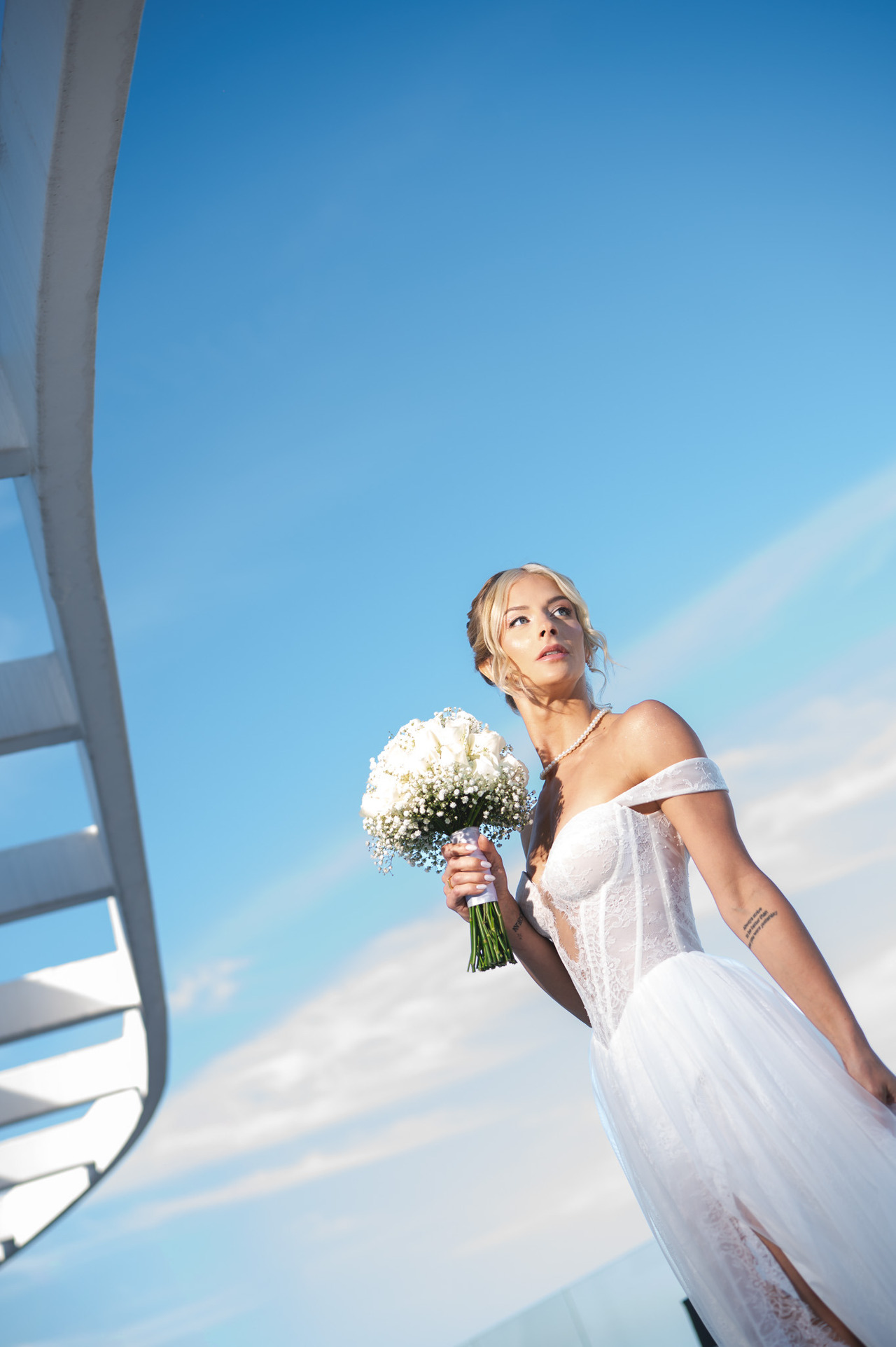 fotografia de casamento, noiva em terraço do hotel c design no recreio dos bandeirantes posa com um céu incrivelmente azul para sua sessão de fotos antes do casamento