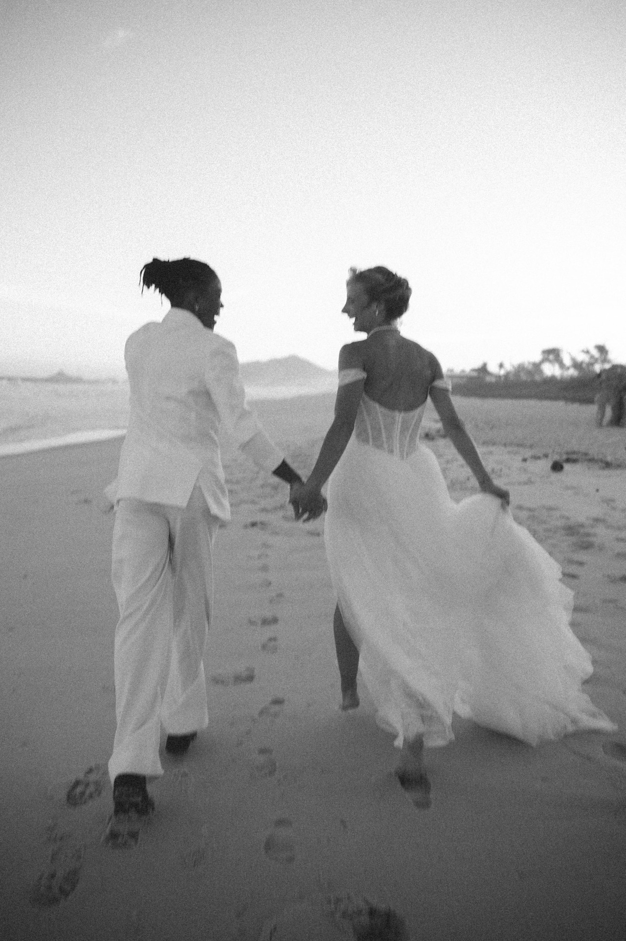 casal de noivas corre na praia em casamento ao por do sol no quiosque som do mar