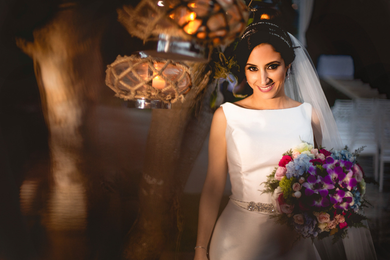 Foto em cores. Noiva com vestido noiva de alça com a pele descoberta rodeando os ossos da clavícula.