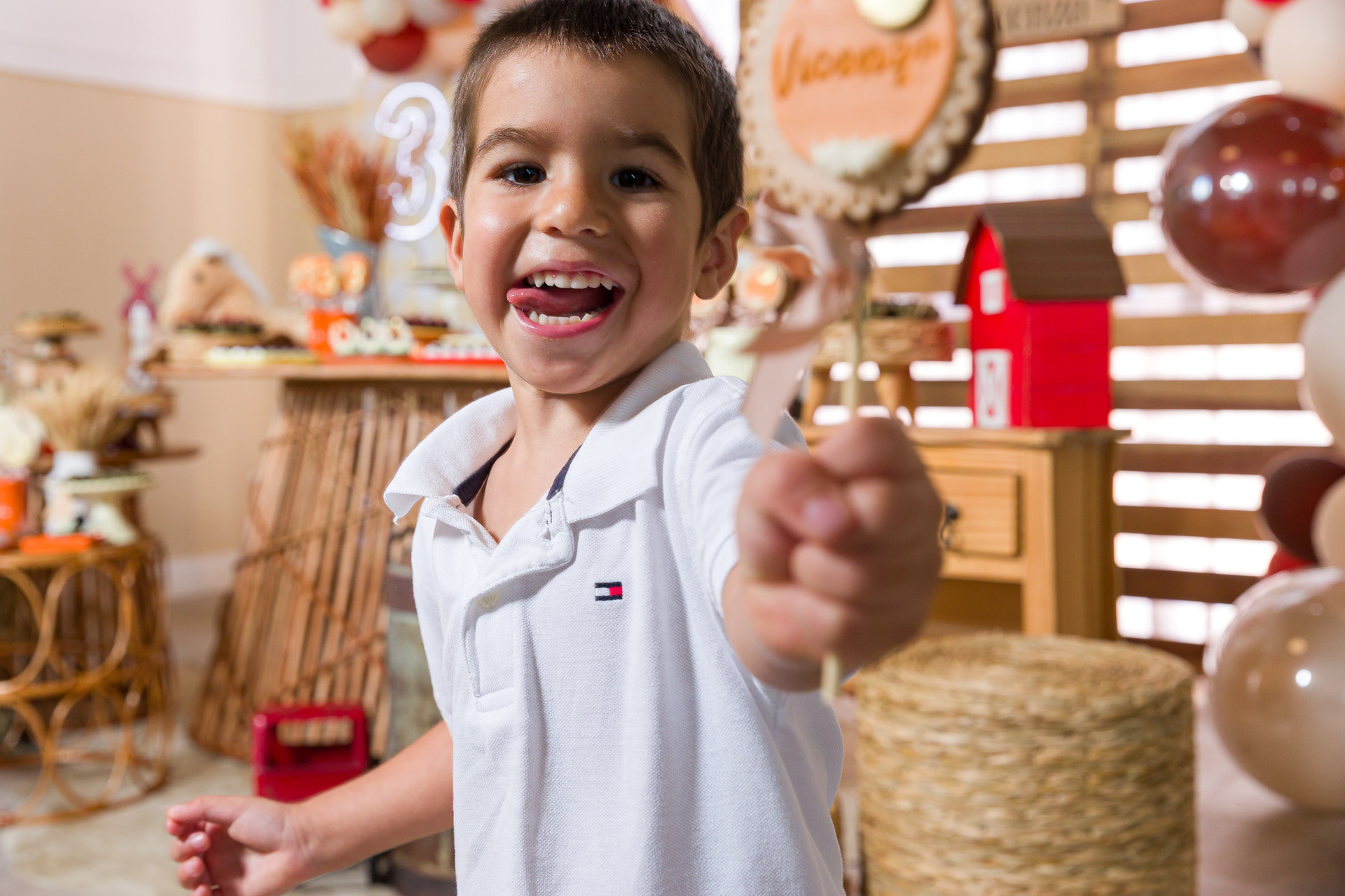 Fotos espontâneas de festa infantil - menino sorrindo e brincando em frente à mesa do bolo