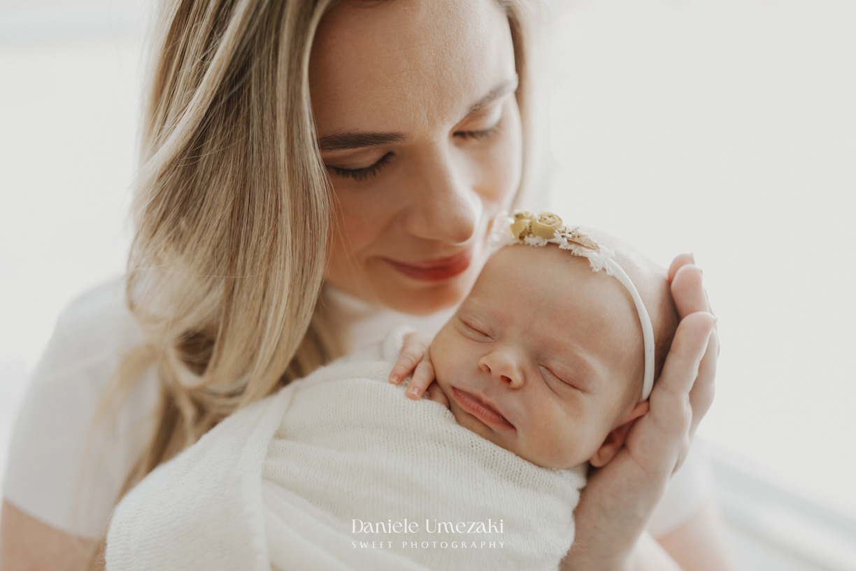 Mãe segurando a recém-nascida Pietra durante ensaio newborn natural realizado em estúdio em Mogi das Cruzes