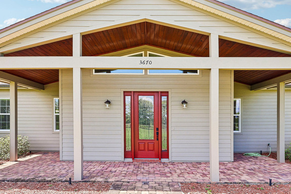 Haines City entry porch showing posts, wood ceiling, brick floor and a red front door.