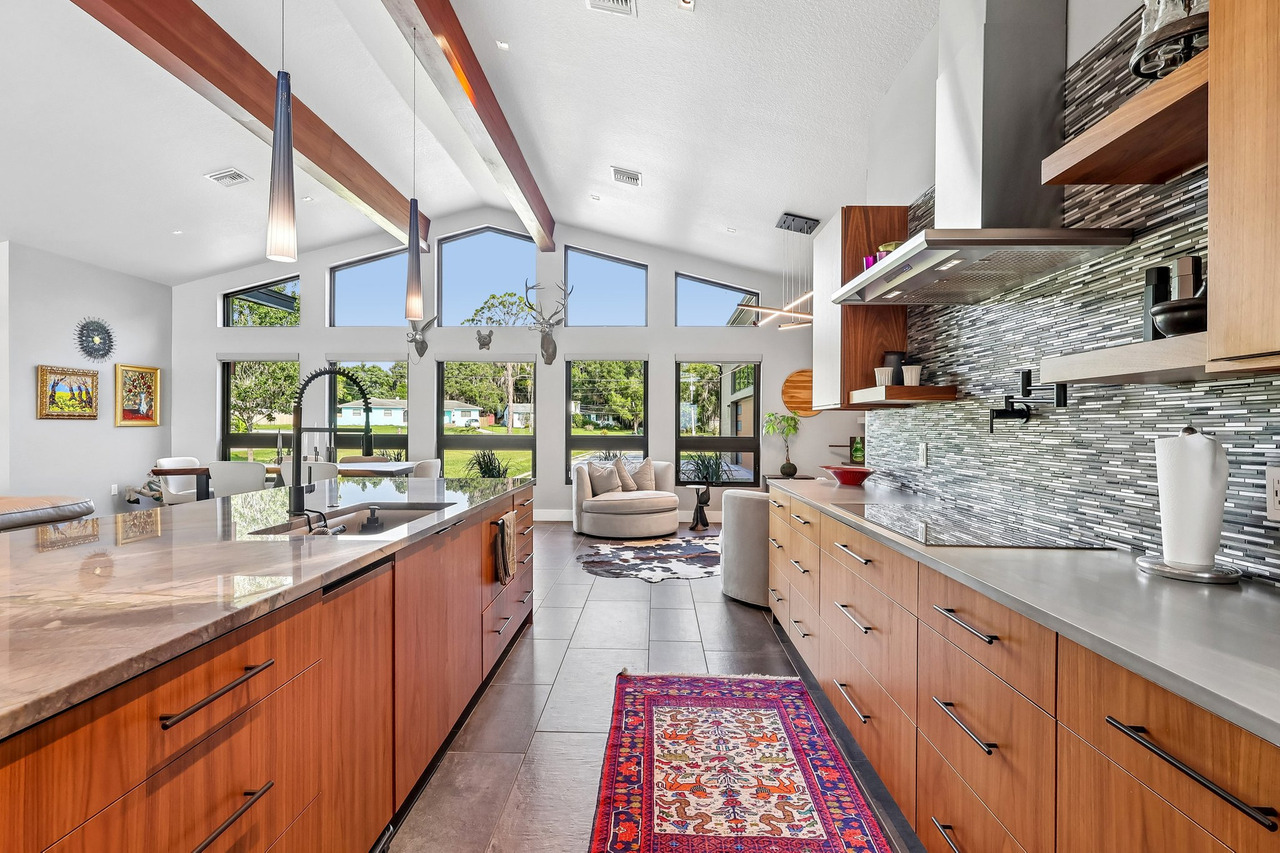 Designer kitchen with wood cabinetry, high ceilings and a bright living area, photographed by Magic Lens