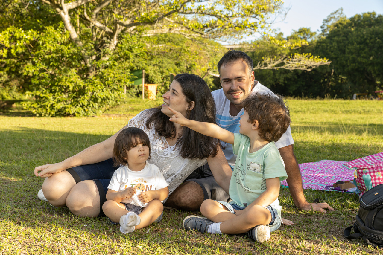Fotografia de família: Família reunida em um gramado ao pôr do sol.