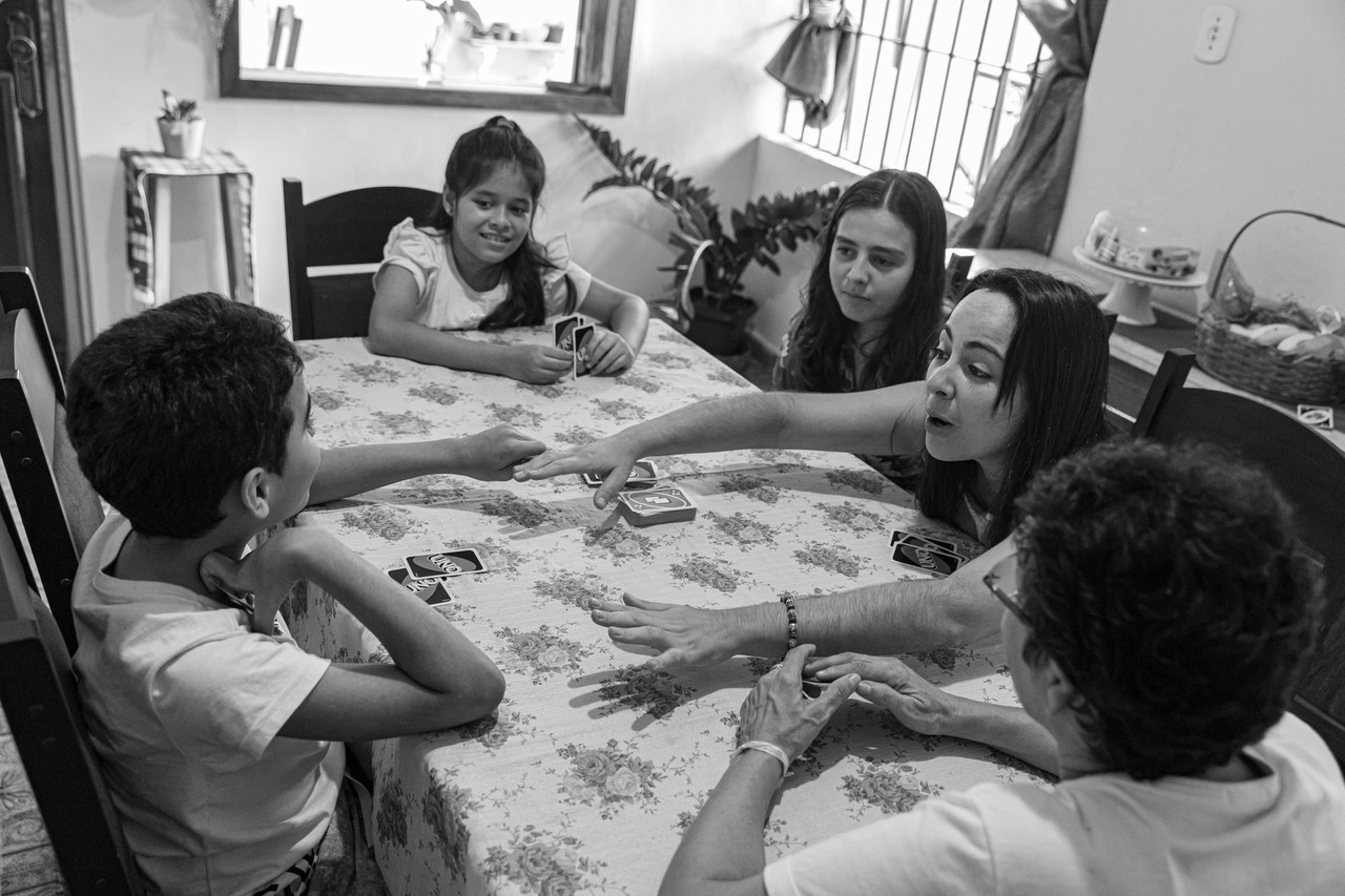 Fotografia de família: Família reunida à mesa jogando baralho