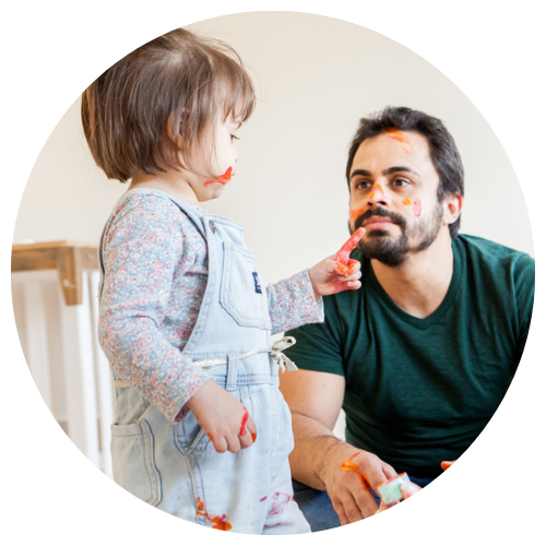 Criança passando tinta no rosto do pai